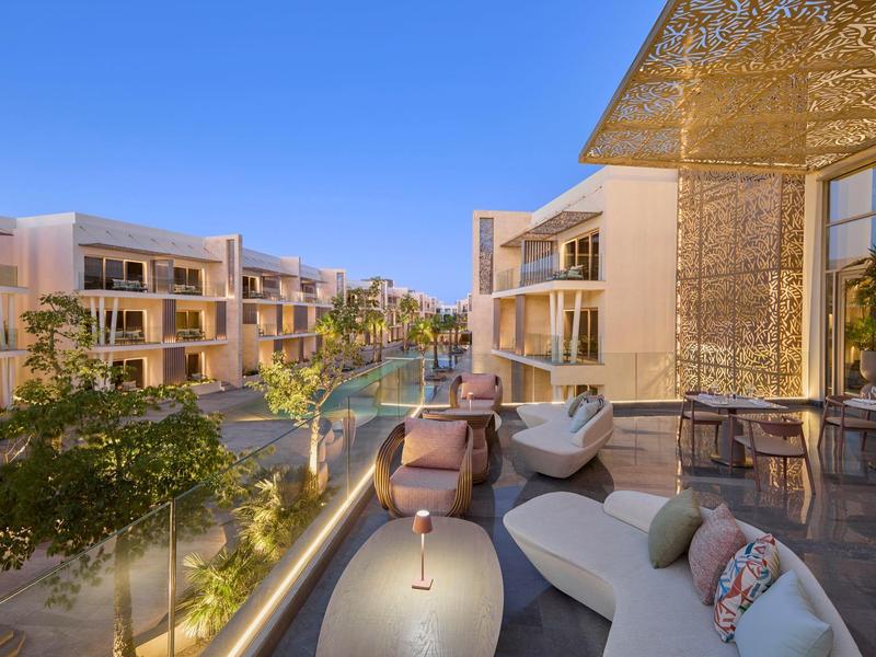 Terrasse d'hôtel moderne avec sièges confortables et vue sur d'autres bâtiments sous un ciel dégagé.