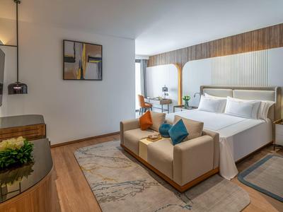 Modern hotel room with double bed and cozy bench at the foot of the bed.