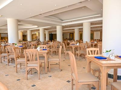 Grand espace de restauration lumineux avec de nombreuses tables et chaises en bois dans un hôtel.