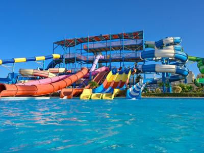 Toboggans colorés au-dessus d'une piscine sous un ciel dégagé dans un parc aquatique.