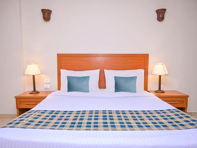 Habitación de hotel moderna con cama doble, dos mesitas de noche y dos lámparas.