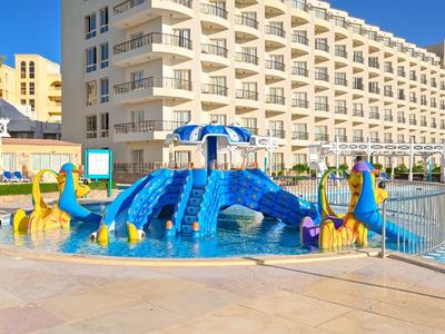 Colorida zona de juegos acuáticos para niños con toboganes en la piscina frente a un gran hotel.