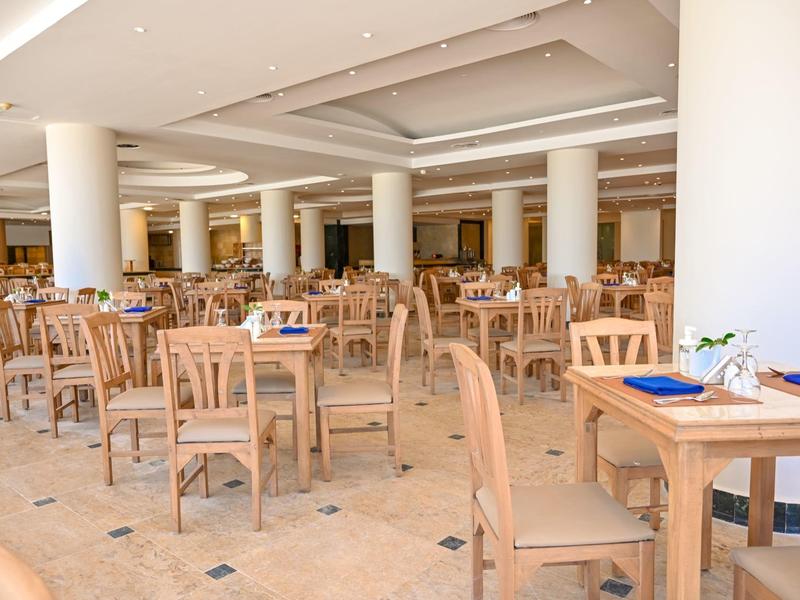 Gran comedor con muchas mesas y sillas de madera en un espacio luminoso y abierto.