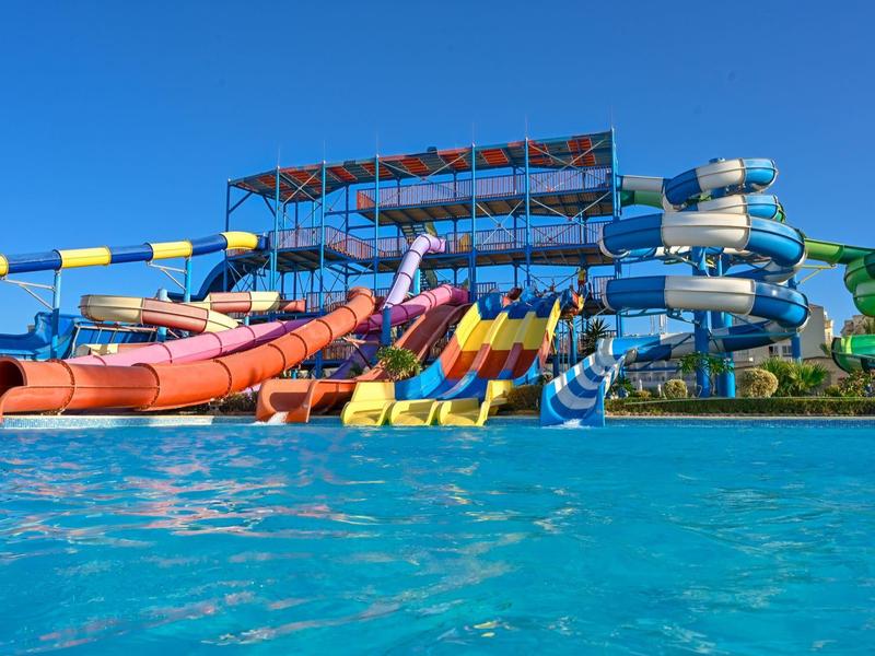 Toboganes acuáticos coloridos sobre una gran piscina bajo un cielo azul despejado.