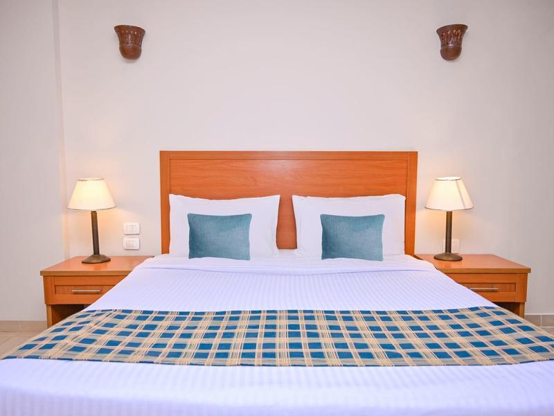 Habitación de hotel moderna con cama doble, dos mesitas de noche y dos lámparas.