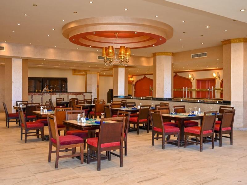 Amplio comedor con mesas de madera y sillas rojas en un restaurante de hotel.