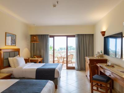 Chambre d'hôtel lumineuse avec deux lits simples et balcon avec vue sur l'eau.