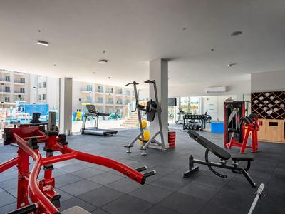 Modern hotel gym with equipment and view of the pool area.