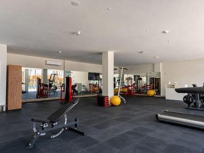 Modern gym with equipment, dumbbells, and large mirror in a hotel setting.