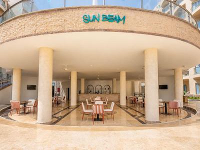 Outdoor seating area of a hotel restaurant with tables and chairs under a round canopy.