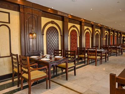 Wnętrze eleganckiej restauracji z drewnianymi meblami i ciepłymi panelami ściennymi.