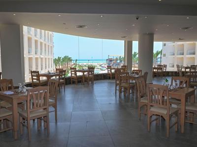 Spacious, bright dining area with wooden tables and sea view.
