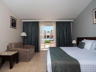 Modern hotel room with double bed, sofa, lamp, and balcony overlooking the city.