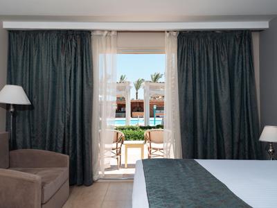 Hotel room overlooking the pool with a terrace and chairs in daylight.