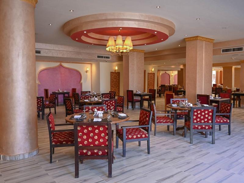 Espace de restauration élégant de l'hôtel avec des chaises confortables et des tables dressées sous des lustres.