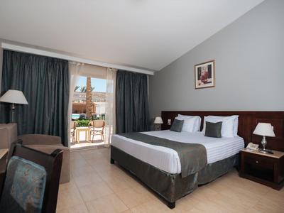 Modern hotelkamer met tweepersoonsbed, balkon en gezellige meubels in neutrale kleuren.
