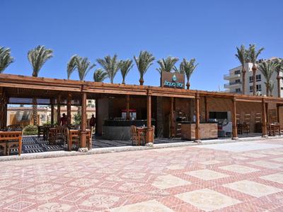 Open strandpaviljoen met houten structuur, tafels, stoelen, palmbomen op de achtergrond
