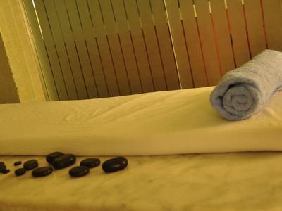 Table de massage avec serviette roulée et pierres de massage noires dans une pièce éclairée chaleureusement