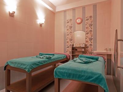 Chambre avec deux tables de massage et une décoration murale sous un éclairage chaleureux.