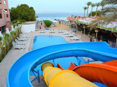 Vue sur une piscine avec toboggans et chaises longues dans un hôtel au bord de la mer.