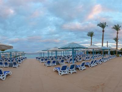 Zone de plage avec chaises longues et parasols au bord de la mer sous un ciel nuageux