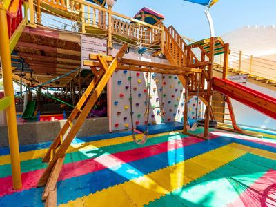 Aire de jeux colorée avec mur d'escalade, toboggan et structures en bois en plein air.