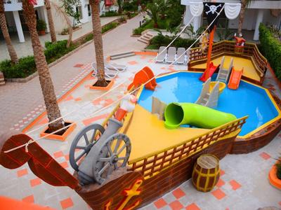 Aire de jeux pour enfants en forme de bateau pirate avec plusieurs toboggans en extérieur.