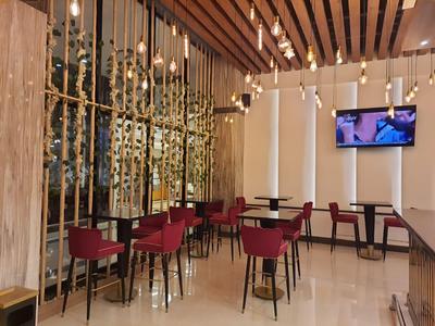 Espace restaurant d'hôtel moderne avec chaises rouges, tables en bois et plafond en bois décoratif.