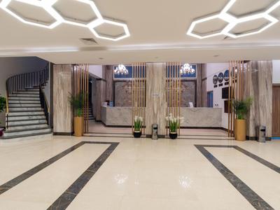 Grand hall d'hôtel avec éclairage moderne, sièges et escalier.