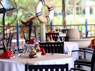 Table élégamment dressée avec nappes blanches et serviettes rouges dans un restaurant en plein air.