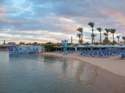 Plage avec chaises longues et palmiers au coucher du soleil au bord d'une mer calme
