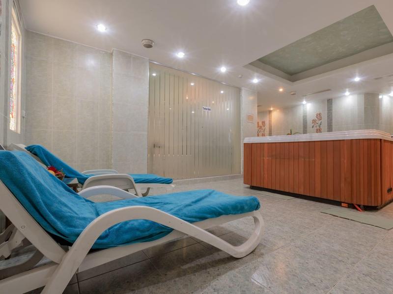 Espace détente avec chaises longues bleues et spa en bois dans un espace bien-être moderne.