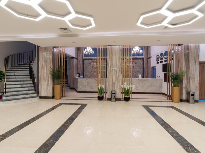 Grand hall d'hôtel avec éclairage moderne, sièges et escalier.