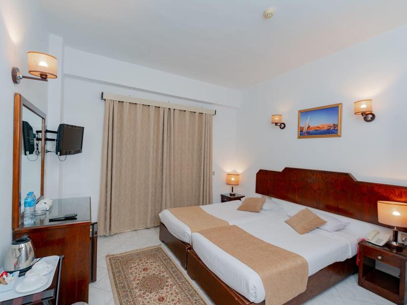 Chambre d'hôtel moderne avec lit double, tables de chevet et télévision murale.