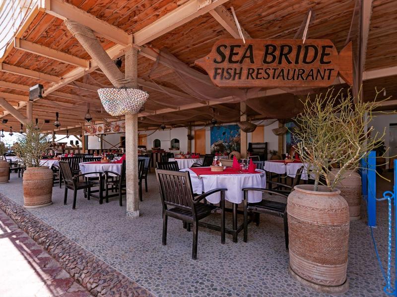 Restaurant ouvert avec toit en bois et tables dressées, enseigne 'Sea Bride Fish Restaurant'