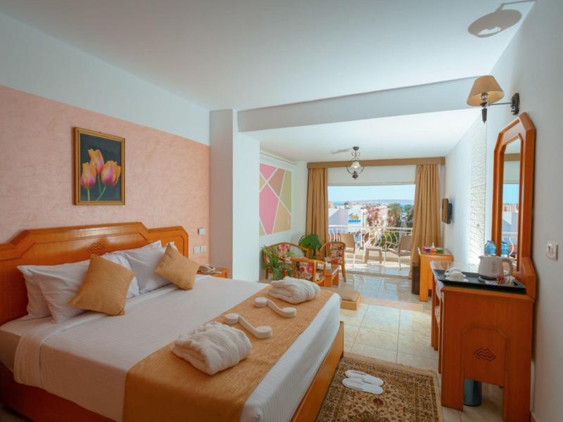 Chambre d'hôtel lumineuse avec lit double, balcon et vue sur la piscine