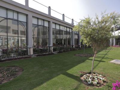 Moderní hotelová zahrada s lesklými skleněnými okny a dobře udržovaným trávníkem.