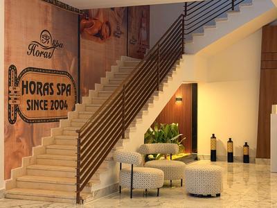 Modern lobby with marble floor, staircase, and lounge seating next to a SPA wall banner.