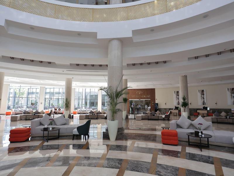 Grand hall d'hôtel lumineux avec des espaces assis et un mobilier moderne.