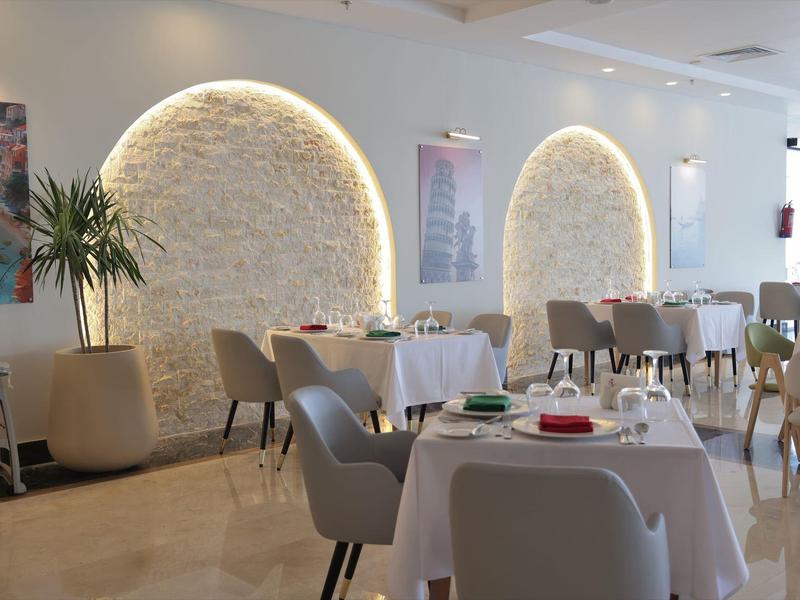 Restaurant moderne avec niches murales arrondies, tables et chaises élégantes, et décoration végétale.