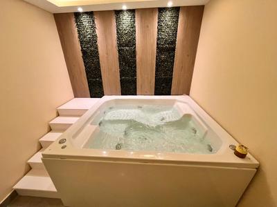 Vasca idromassaggio moderna con bolle in una stanza beige con pareti in pietra illuminate.