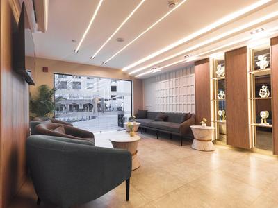 Area d'attesa moderna con divani, poltrone e pavimento in legno chiaro in un hotel.