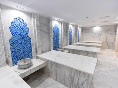 Hammam moderno con lastre in marmo e piastrelle blu alle pareti.