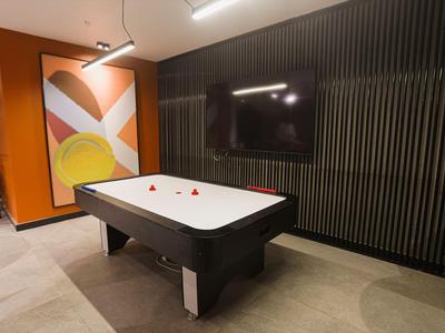 Tavolo da biliardo moderno in una stanza con pannelli murali neri e arte murale colorata.