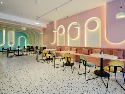 Ristorante d'hotel moderno con pareti color pastello, linee illuminate e sedie eleganti.