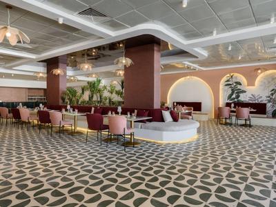 Elegante hall dell'hotel con aree salotto, pavimento a piastrelle geometriche e illuminazione moderna.