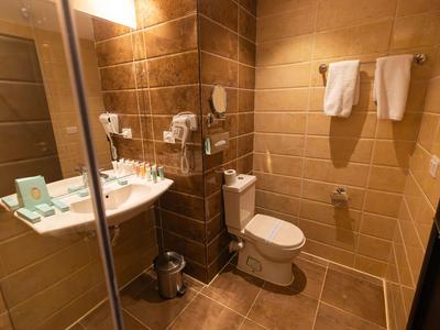 Bagno moderno dell'hotel con toilette, lavabo e asciugamani appesi al muro.