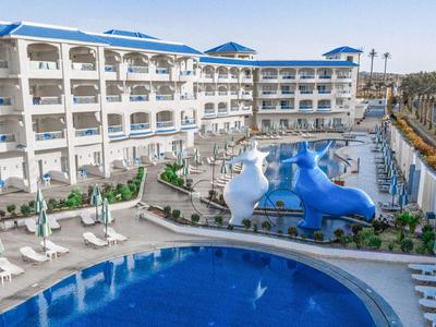 Hotel con grande piscina all'aperto e scivolo d'acqua, circondato da lettini e palme.