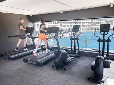 Due persone corrono su tapis roulant in una palestra con vista sul mare.