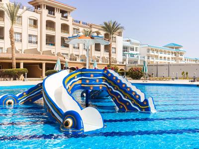 Scivolo d'acqua nell'area piscina dell'hotel con palme e edificio a più piani sullo sfondo.